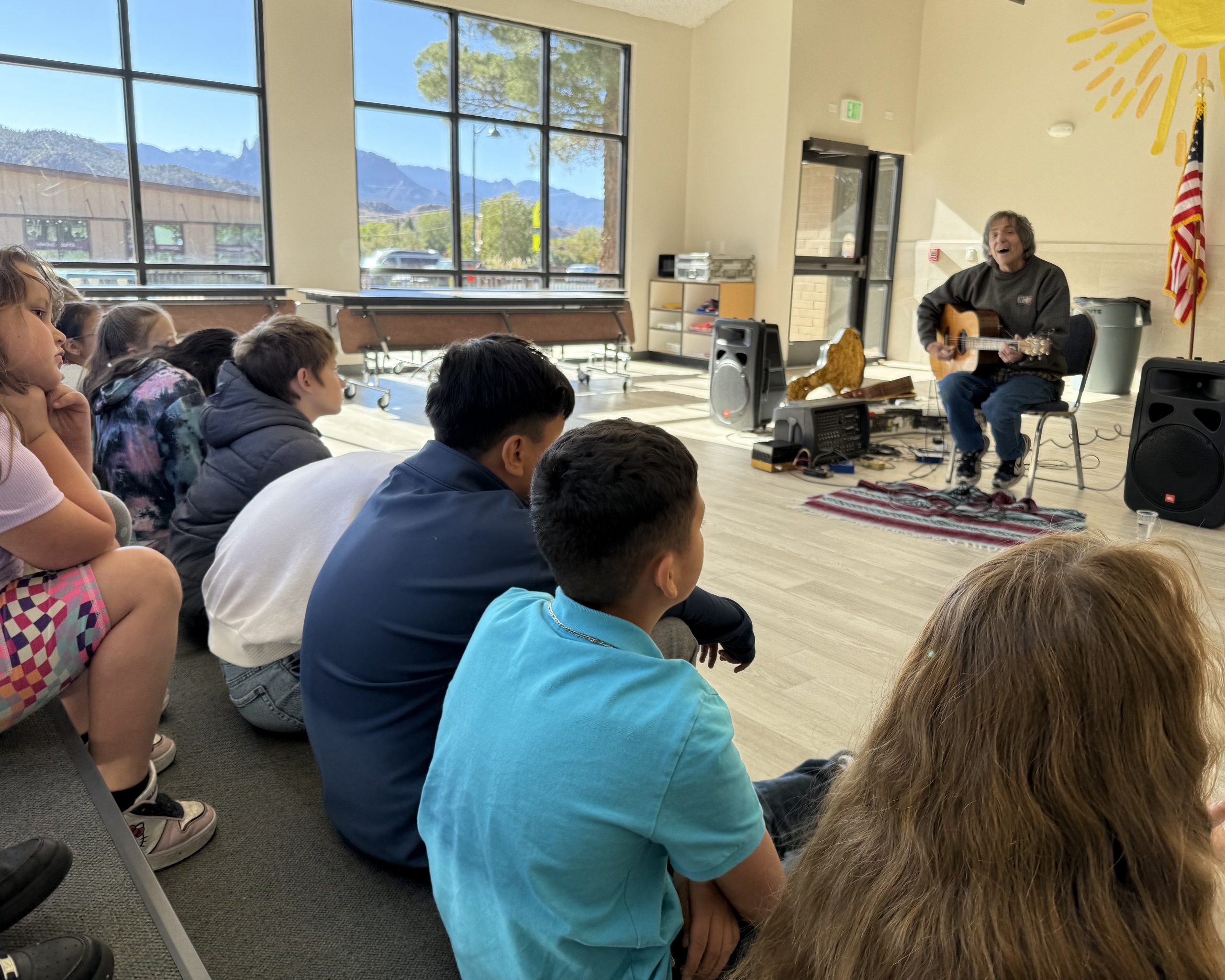 Musician Michael Gulezian playing guitar and talking with the students.