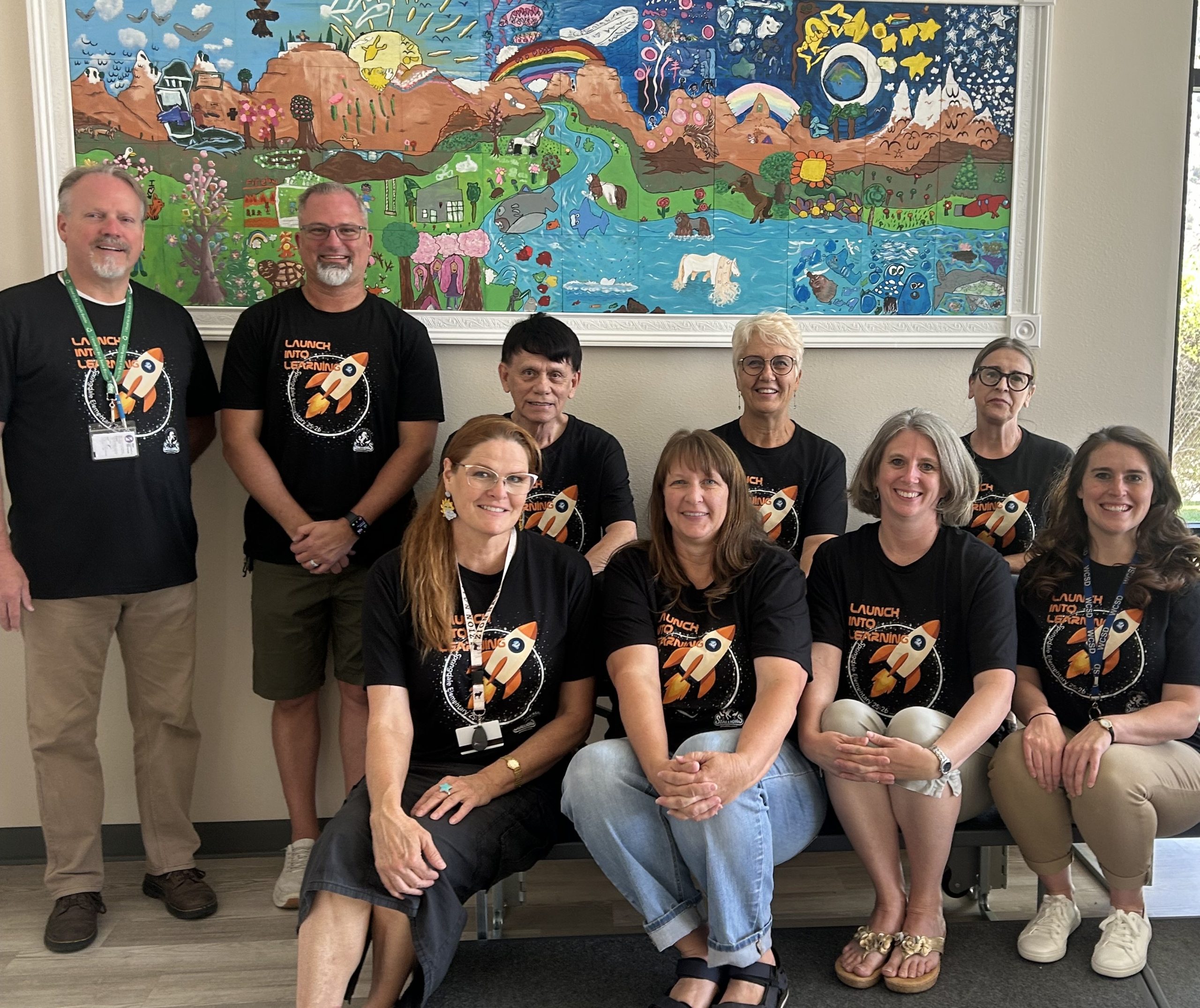 Springdale Staff members posing in front of a student painted mural.