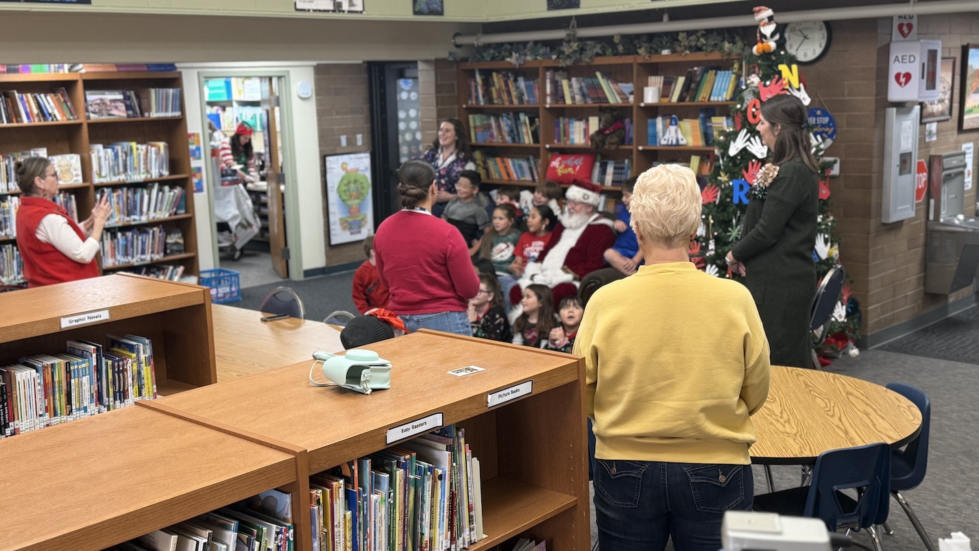 Santa Claus posing with students for a picture with staff members taking pictures.